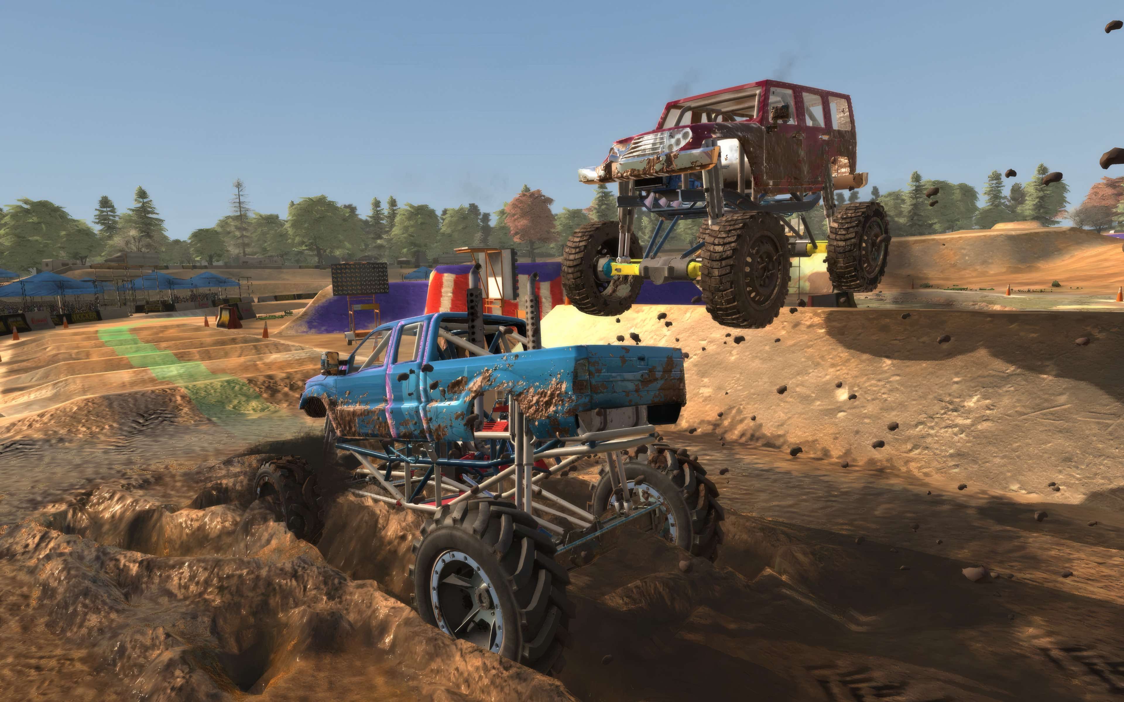 Mega truck jumping over a mud-splashed truck on a dirt circuit